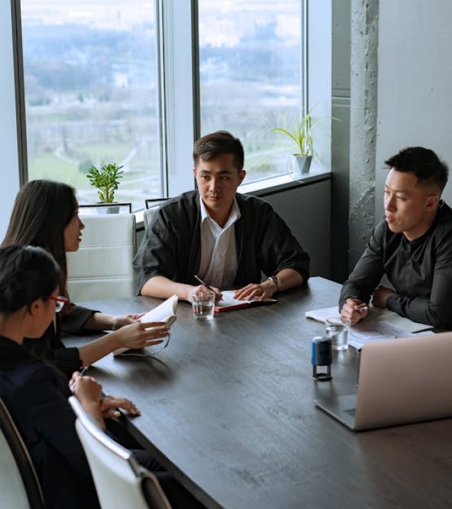 Group of Asian professionals having a meeting in a modern office setting.